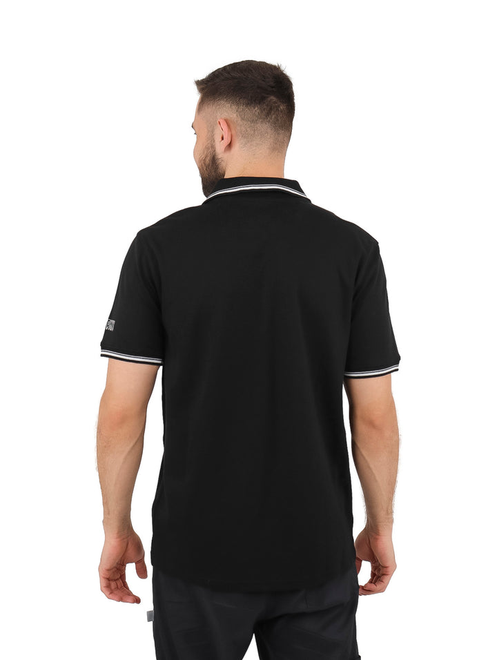 Hombre vistiendo una playera polo negra de manga corta con detalles blancos en el cuello y mangas.