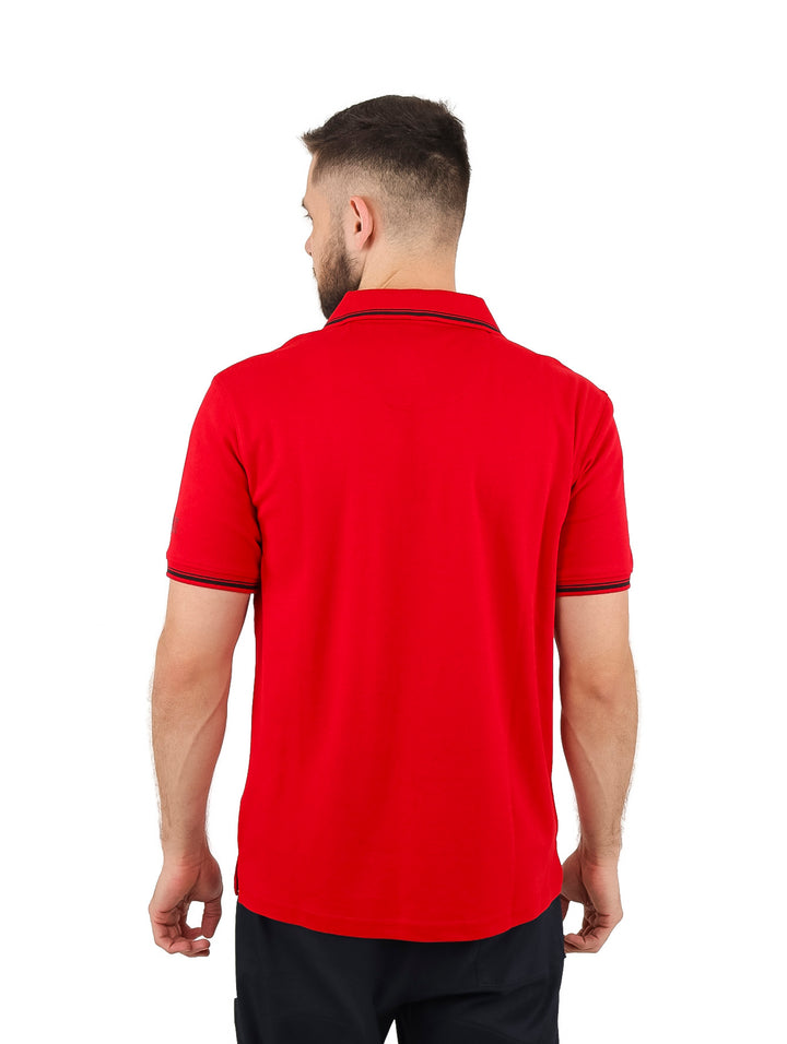 Hombre vistiendo playera polo color rojo con cuello y mangas detallados en negro y cierre frontal.