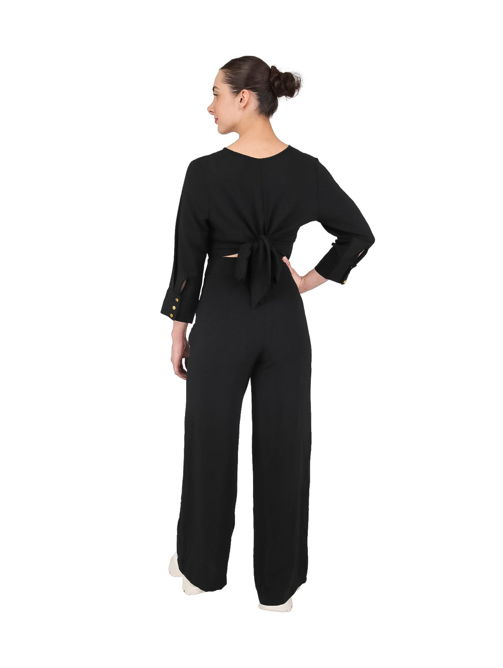 Mujer vistiendo un conjunto de dos piezas en color negro compuesto por un top corto y pantalón ancho.