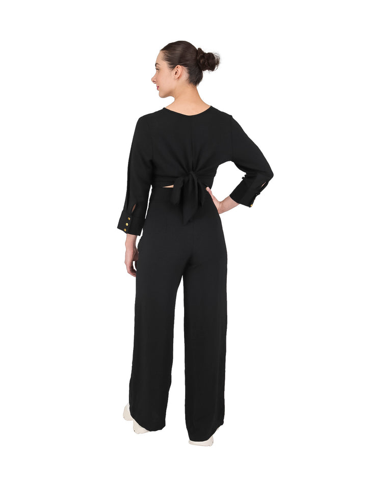 Mujer vistiendo un conjunto de dos piezas en color negro compuesto por un top corto y pantalón ancho.
