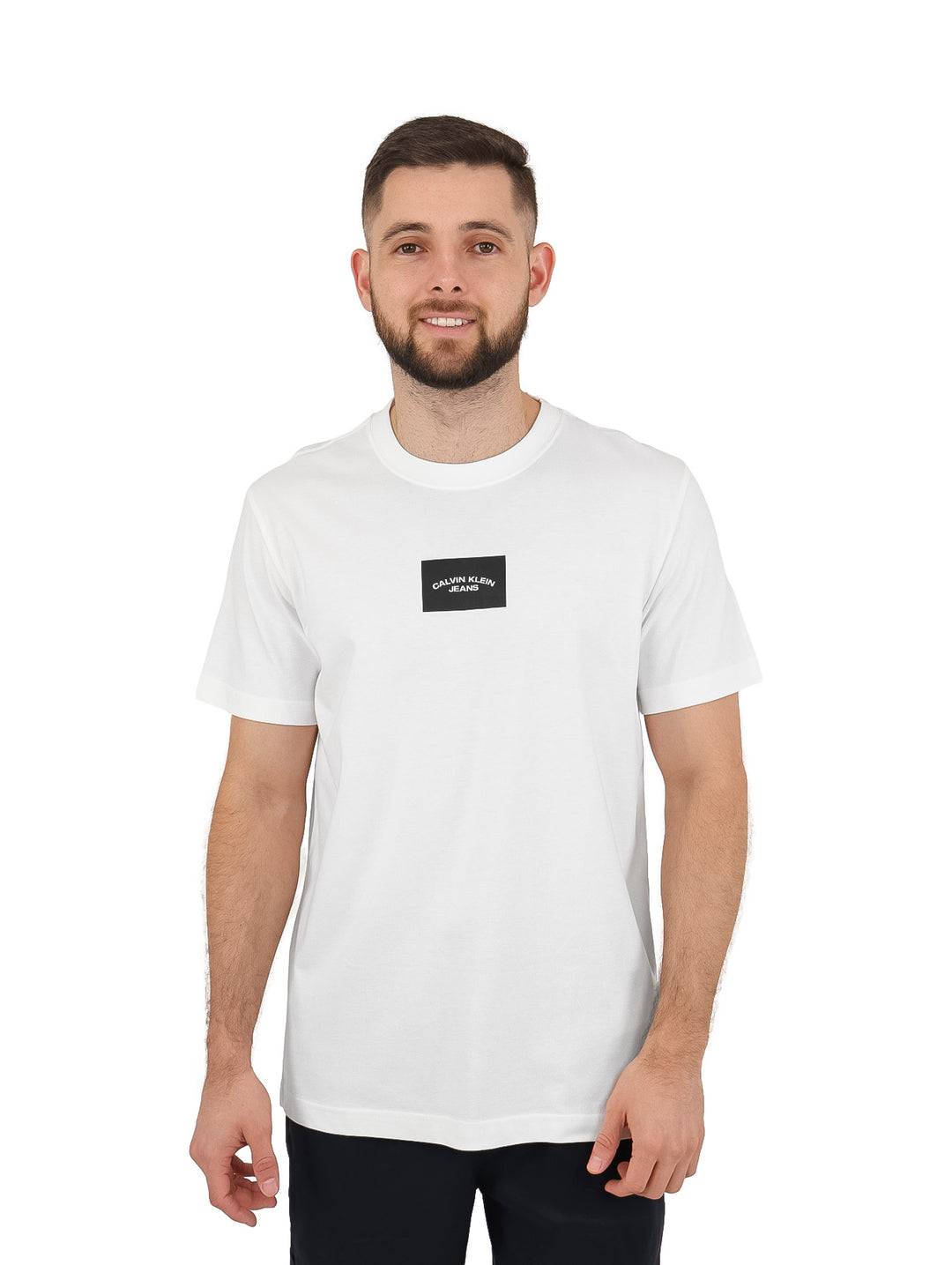 Hombre vistiendo una camiseta blanca de manga corta con un pequeño logo negro centrado de Calvin Klein.