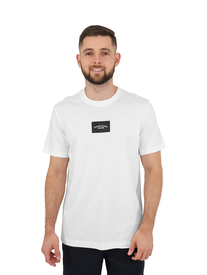 Hombre vistiendo una camiseta blanca de manga corta con un pequeño logo negro centrado de Calvin Klein.