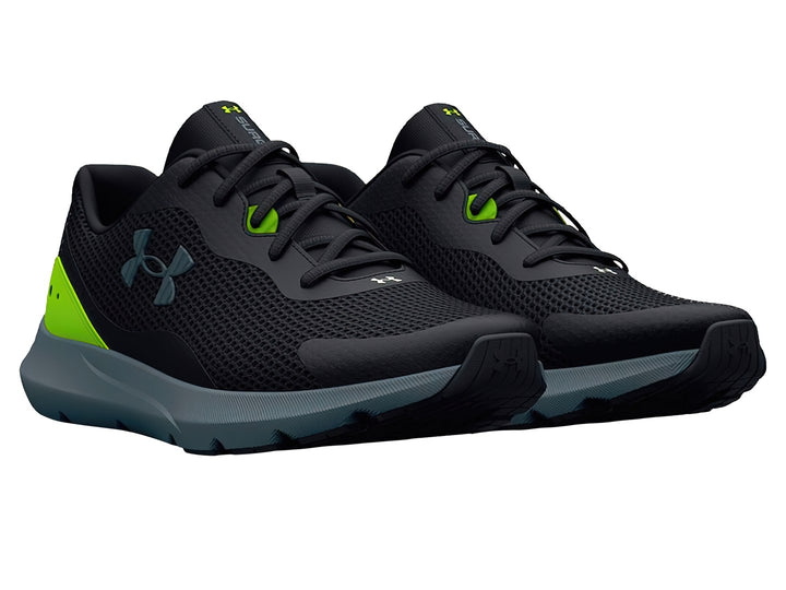 Zapato deportivo Under Armour color negro con detalles en verde neón y suela gris oscuro.