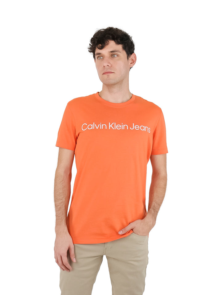 Hombre vistiendo una camiseta naranja de manga corta con el logo de Calvin Klein Jeans en blanco.