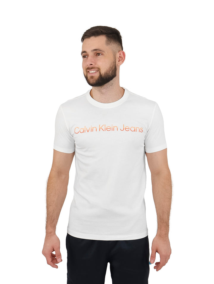 Hombre vistiendo una camiseta blanca de manga corta con el logo de Calvin Klein Jeans en el pecho.
