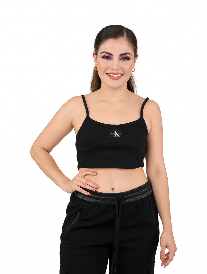 Mujer vistiendo un bralette negro de Calvin Klein con tirantes delgados y pantalones negros.