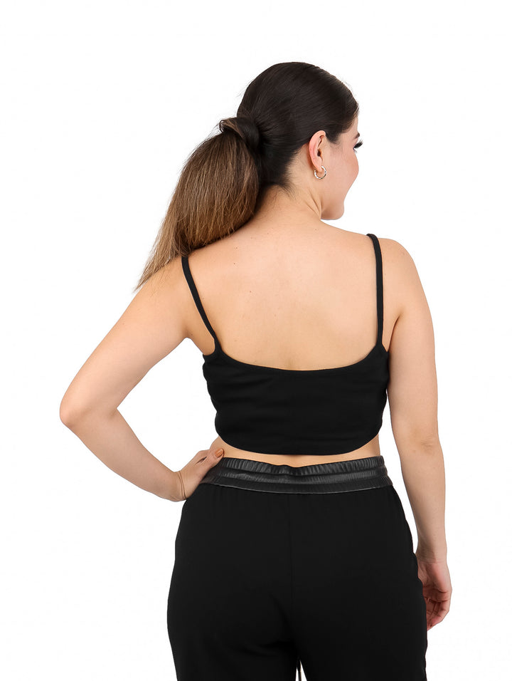 Mujer vistiendo un bralette negro de Calvin Klein con tirantes delgados y pantalones negros.