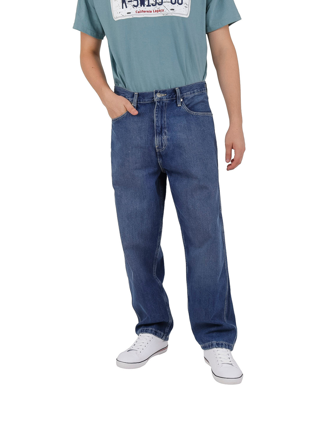 Hombre vistiendo pantalones de mezclilla azules estilo carpenter de corte recto y calzado blanco.
