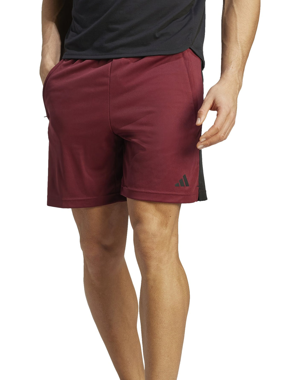 Hombre vistiendo shorts deportivos Adidas color guinda con paneles laterales negros.