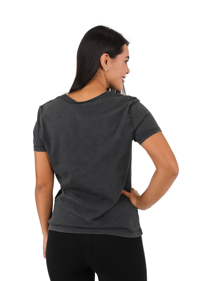 Mujer vistiendo blusa negra de manga corta con estampado artístico de animal en tonos dorado y blanco.