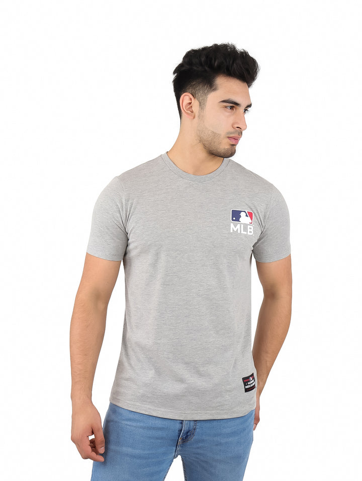 Hombre vistiendo una playera gris de manga corta con el logo de la MLB en el pecho.
