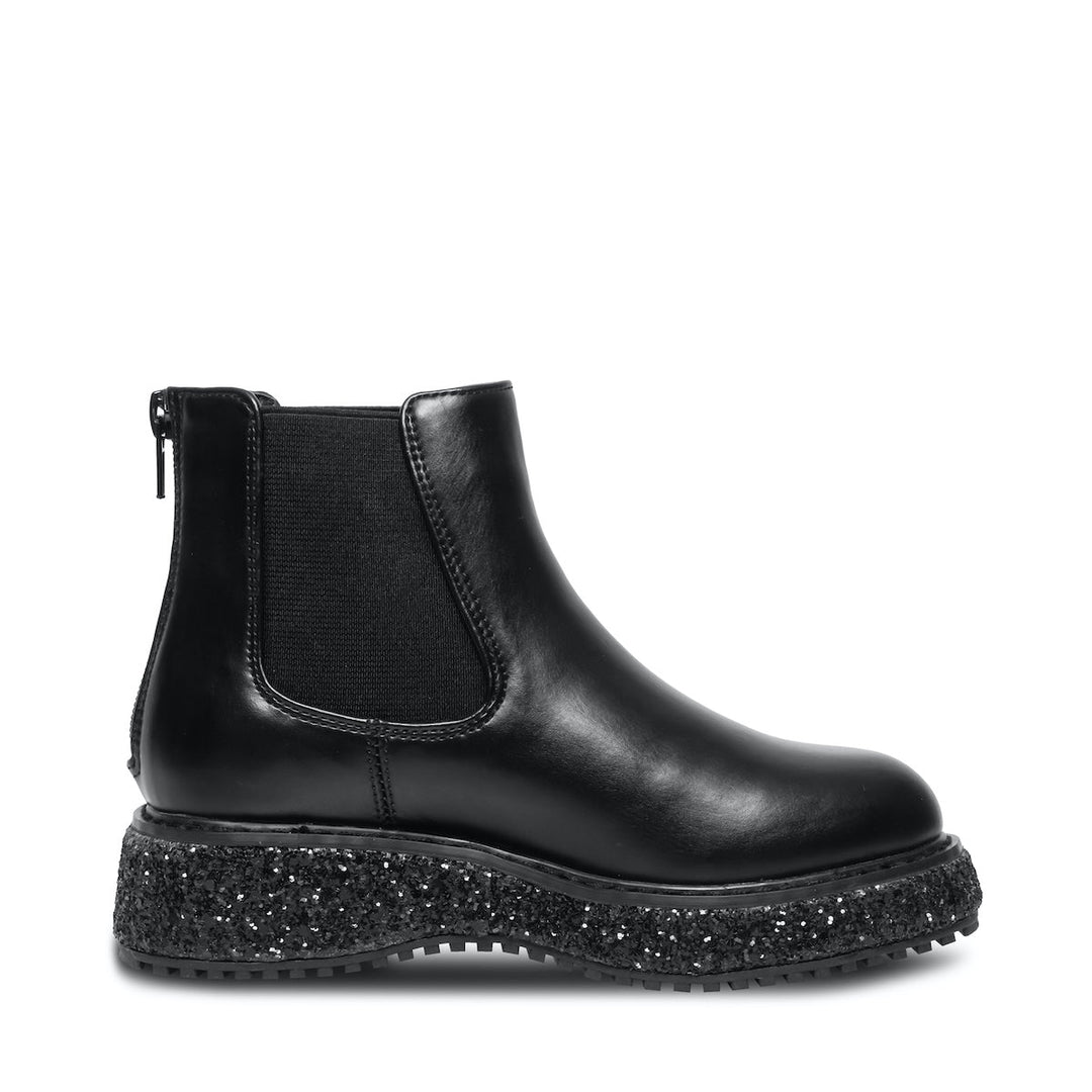 Botas negras Steve Madden con suela gruesa moteada en blanco y negro, acabado brillante y cierre lateral.
