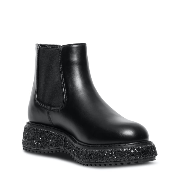 Botas negras Steve Madden con suela gruesa moteada en blanco y negro, acabado brillante y cierre lateral.