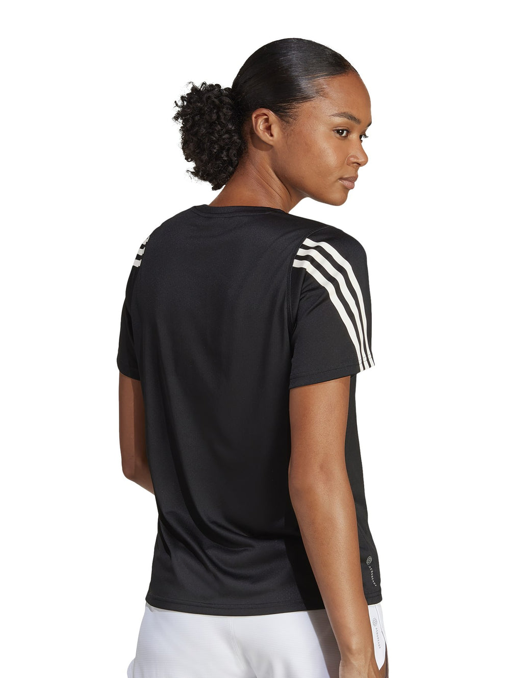 Mujer vistiendo camiseta deportiva Adidas de color negro con rayas blancas en los hombros.