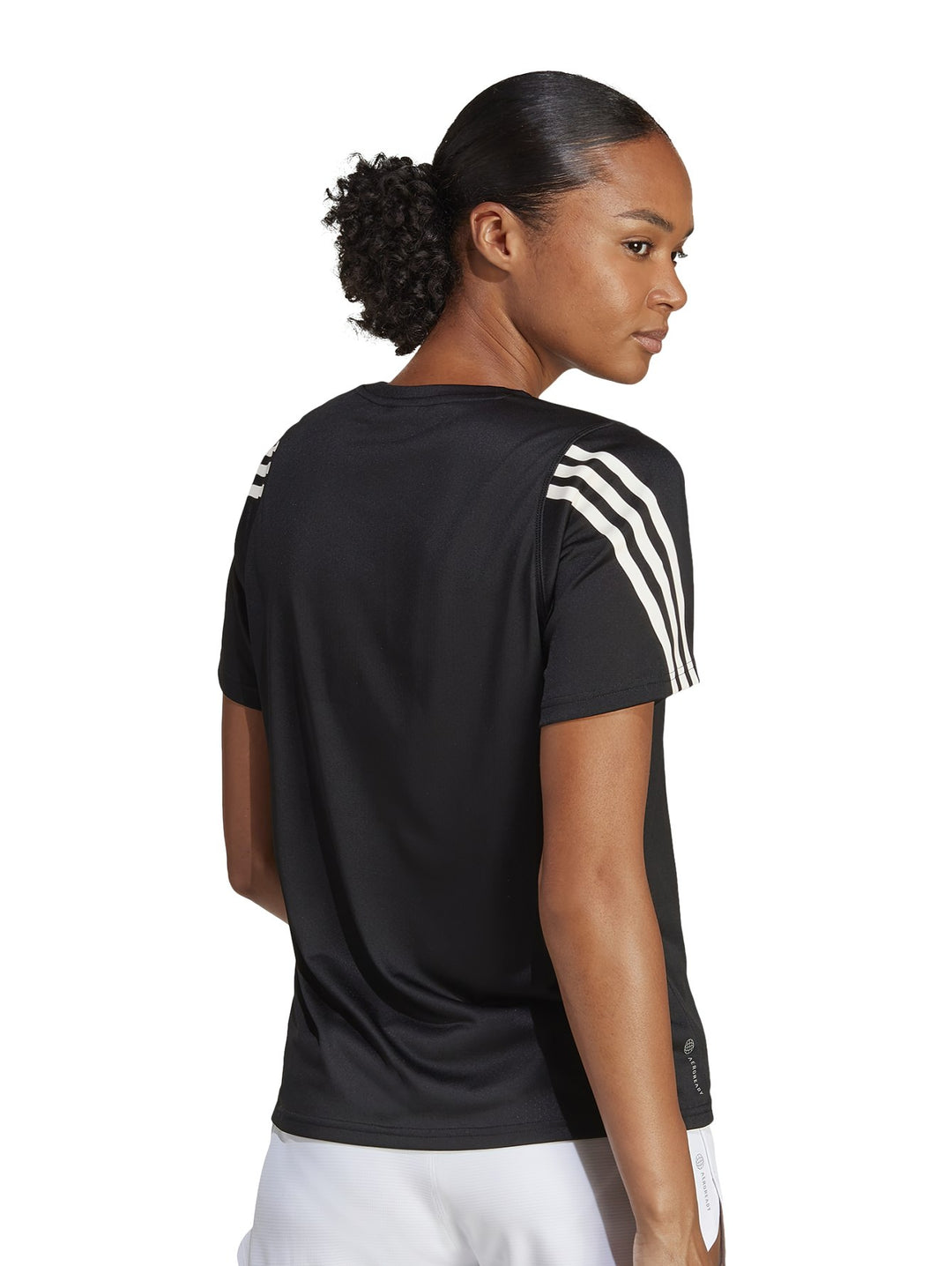 Mujer vistiendo camiseta deportiva Adidas de color negro con rayas blancas en los hombros.