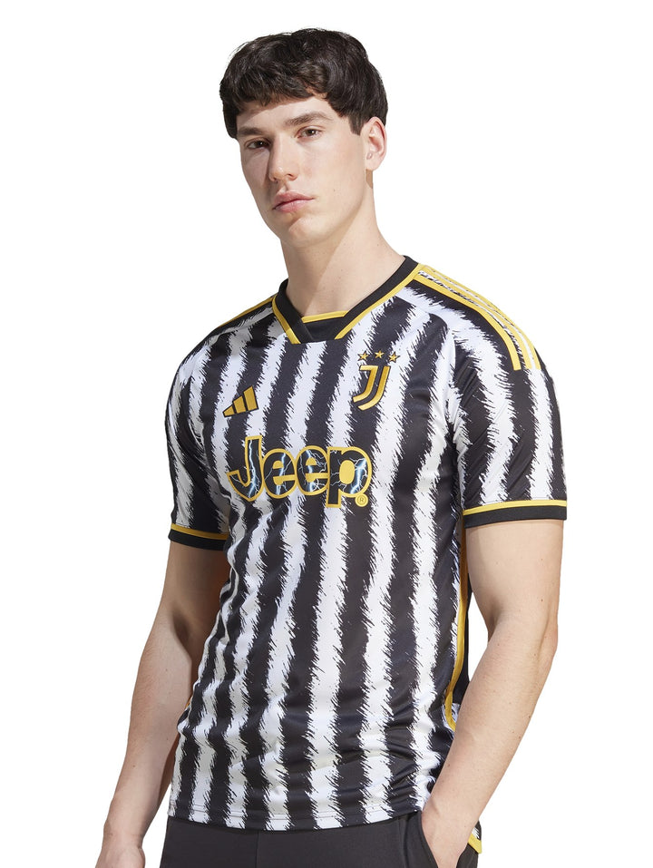 Hombre vistiendo camiseta de fútbol Adidas de la Juventus con rayas verticales negras y blancas y detalles amarillos.