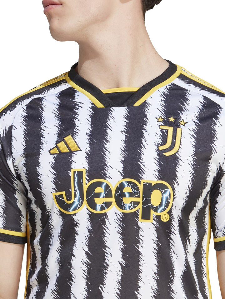 Hombre vistiendo camiseta de fútbol Adidas de la Juventus con rayas verticales negras y blancas y detalles amarillos.