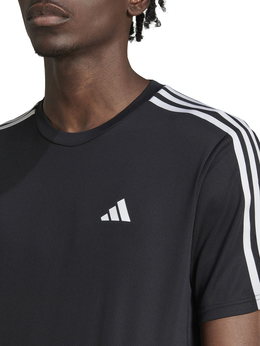 Hombre vistiendo playera deportiva Adidas color negro con tres franjas blancas en los hombros y logo blanco al pecho.