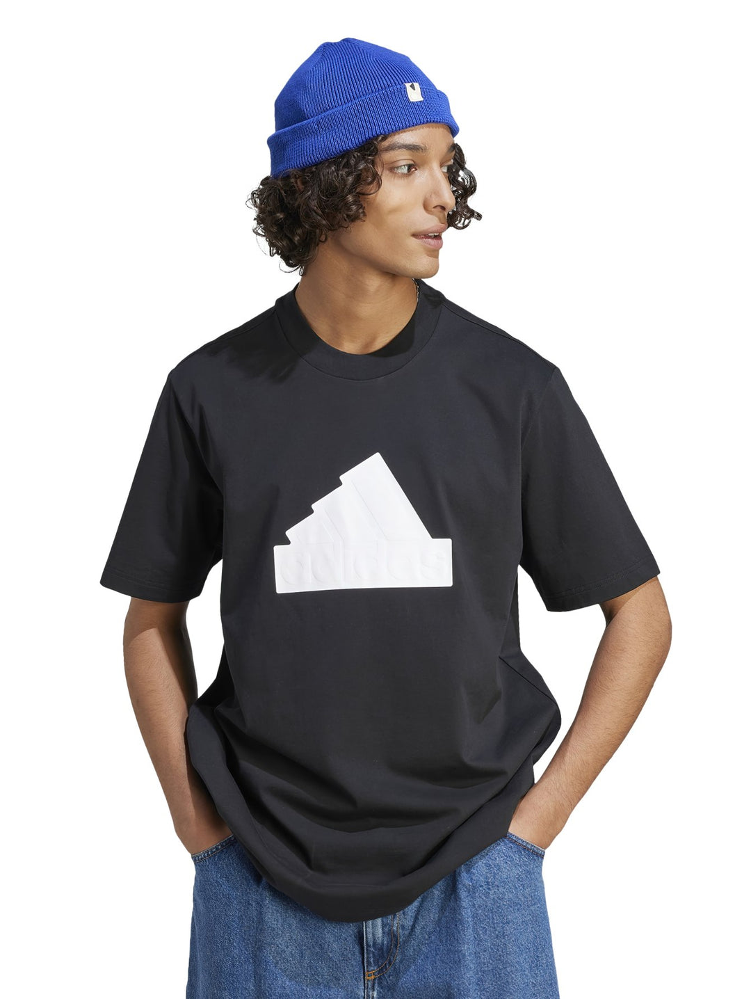 Hombre usando camiseta negra Adidas con gráfico blanco, gorro azul y pantalones mezclilla.