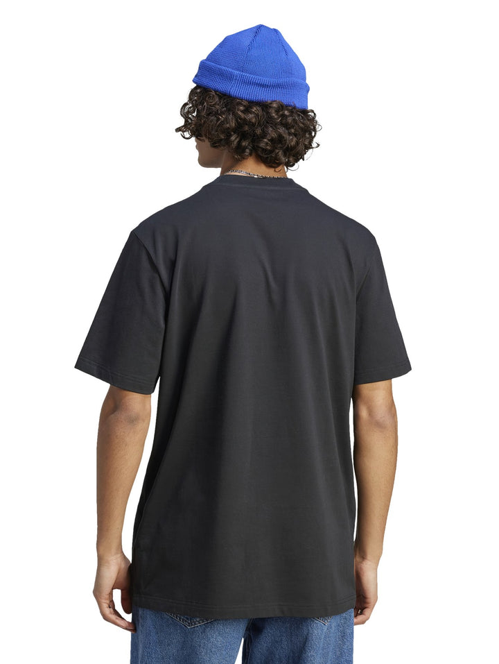 Hombre usando camiseta negra Adidas con gráfico blanco, gorro azul y pantalones mezclilla.