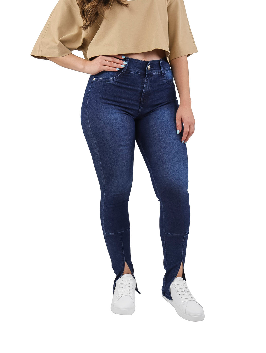Mujer vistiendo pantalones jeans ajustados color azul oscuro con aberturas laterales en los tobillos.