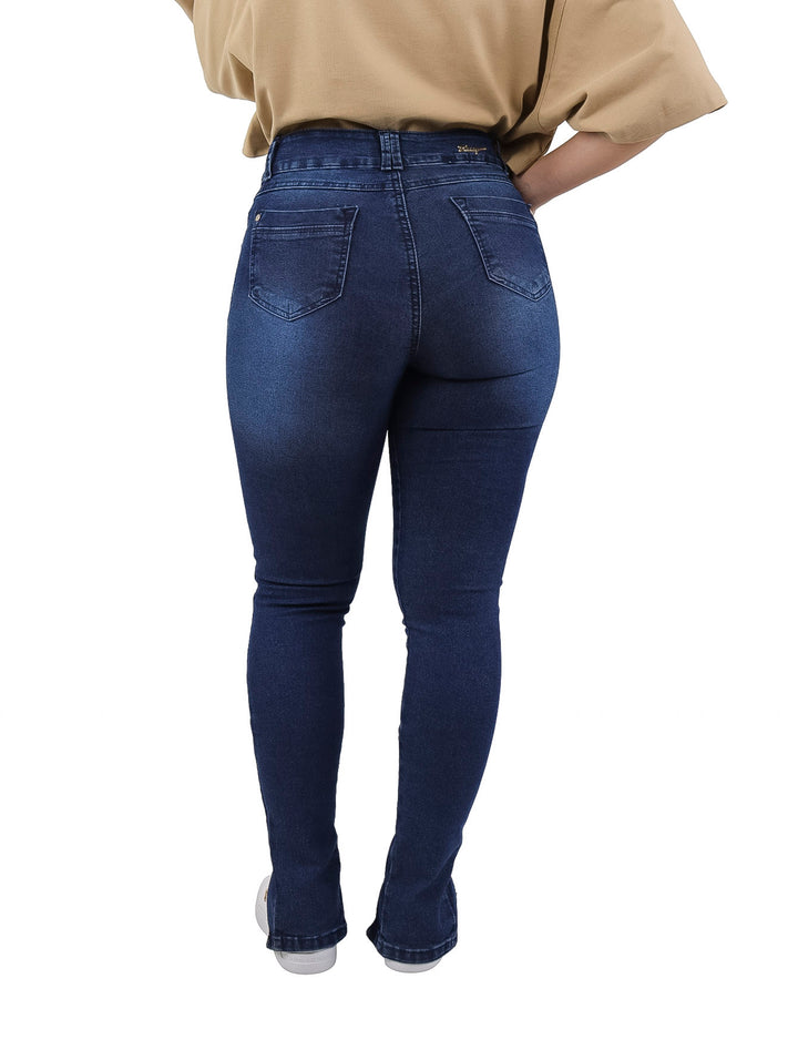 Mujer vistiendo pantalones jeans ajustados color azul oscuro con aberturas laterales en los tobillos.