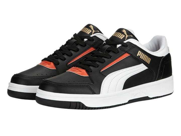 Tenis PUMA Rebound Joy Low en color negro con detalles en blanco y naranja, suela blanca y corte bajo.