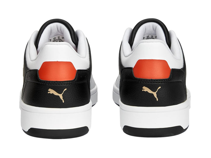 Tenis PUMA Rebound Joy Low en color negro con detalles en blanco y naranja, suela blanca y corte bajo.