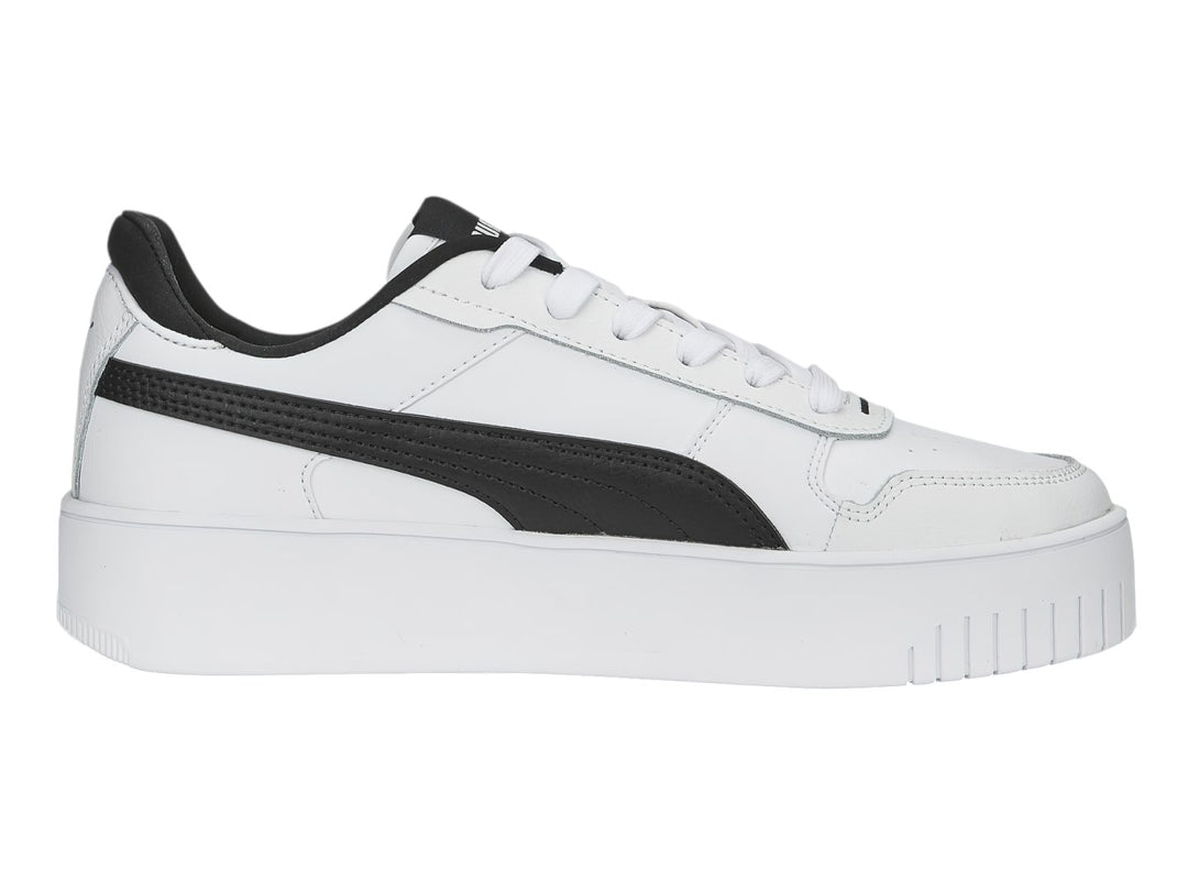 Tenis Puma blancos con franja lateral negra y suela de plataforma blanca.