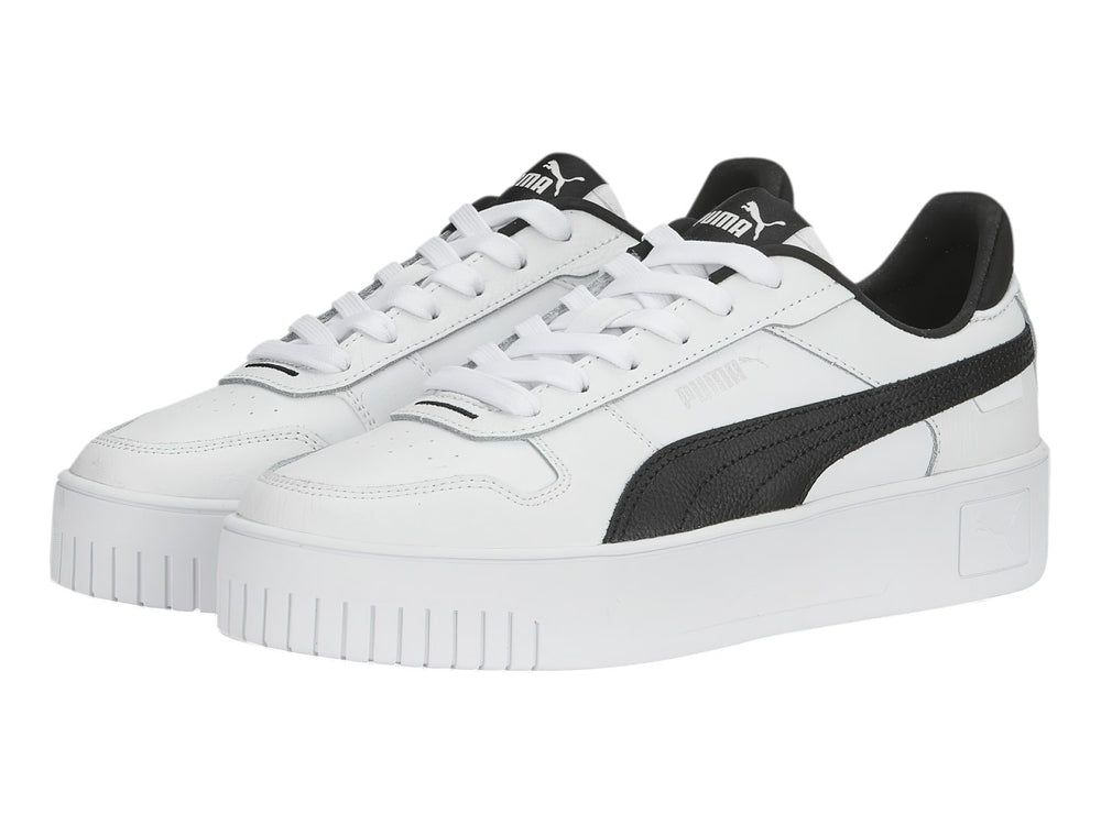 Tenis Puma blancos con franja lateral negra y suela de plataforma blanca.