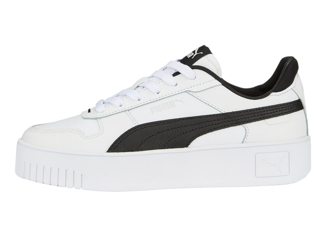 Tenis Puma blancos con franja lateral negra y suela de plataforma blanca.