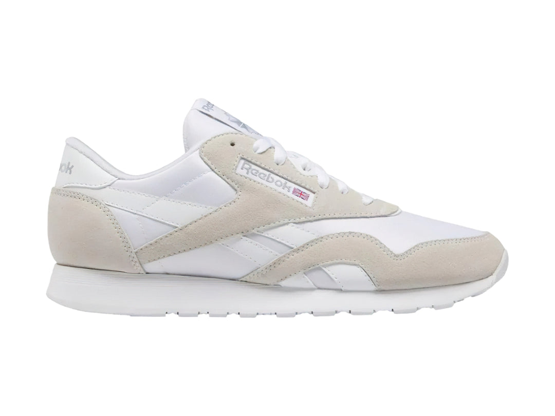 Tenis Reebok blancos de corte bajo con detalles en gamuza clara y suela blanca.
