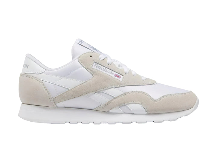 Tenis Reebok blancos de corte bajo con detalles en gamuza clara y suela blanca.
