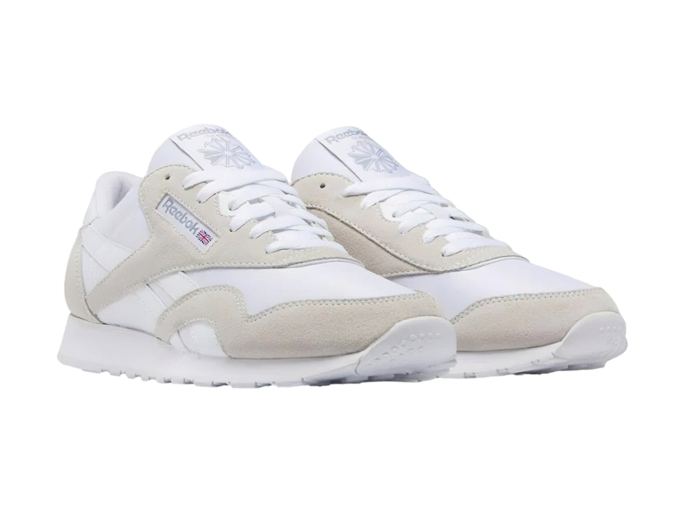 Tenis Reebok blancos de corte bajo con detalles en gamuza clara y suela blanca.