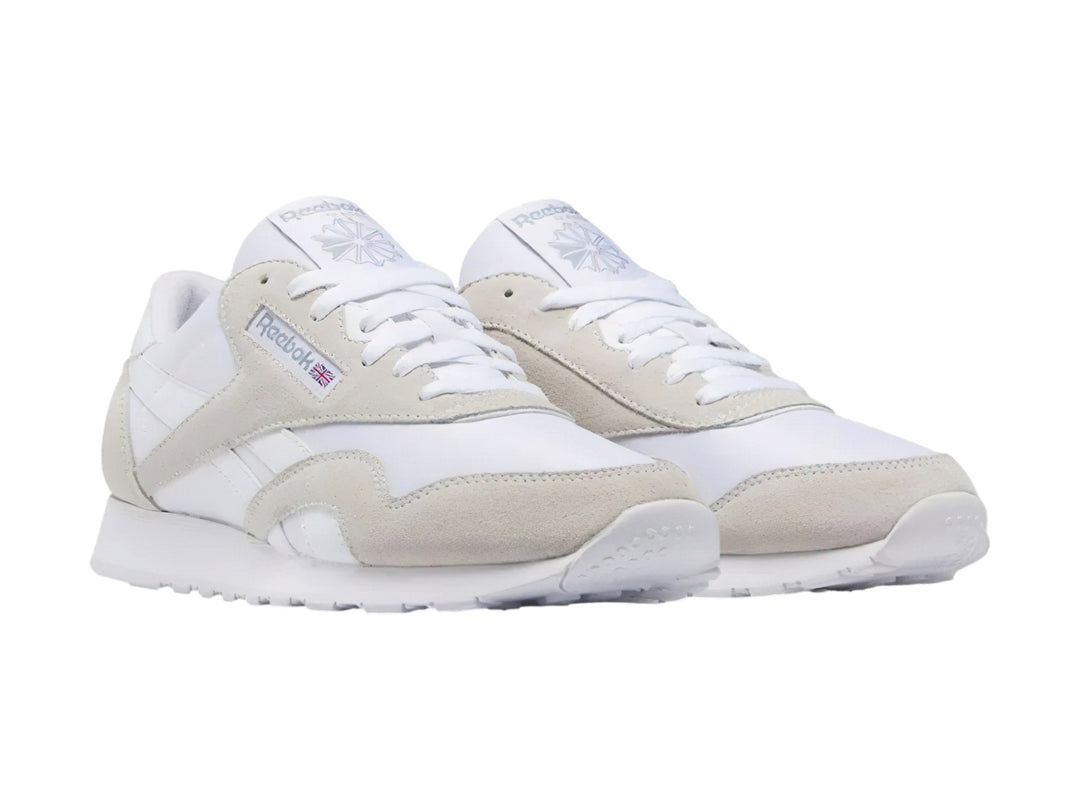 Tenis Reebok blancos de corte bajo con detalles en gamuza clara y suela blanca.