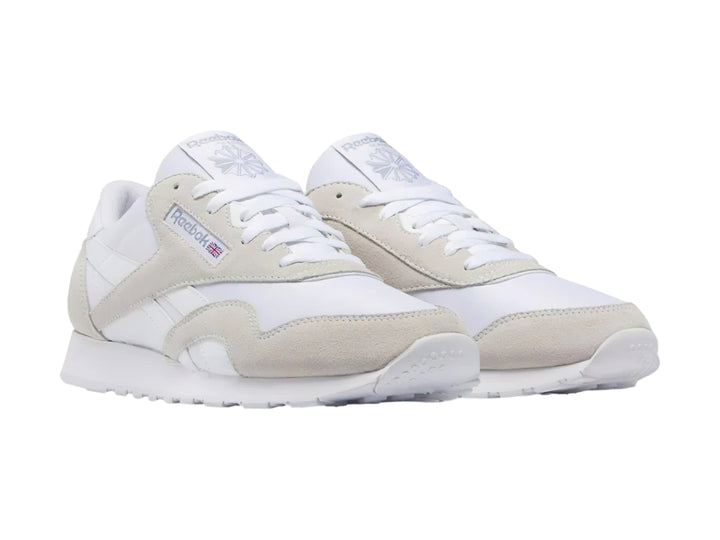 Tenis Reebok blancos de corte bajo con detalles en gamuza clara y suela blanca.