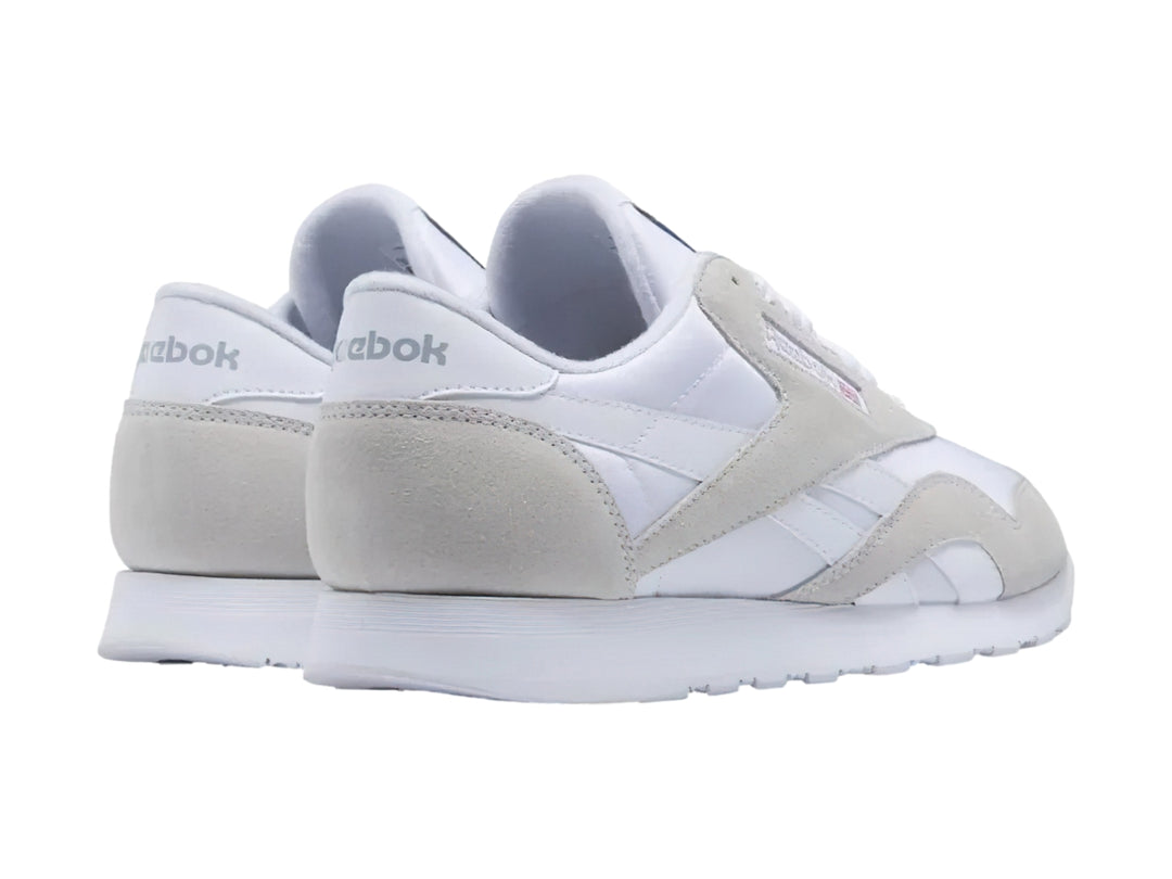 Tenis Reebok blancos de corte bajo con detalles en gamuza clara y suela blanca.