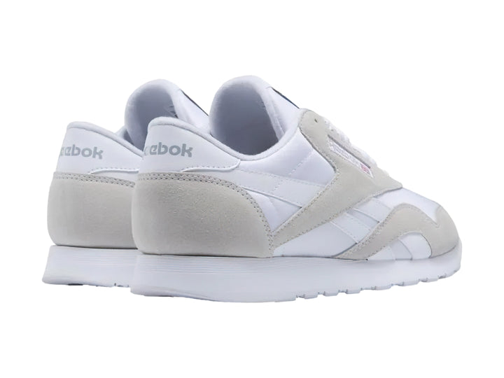 Tenis Reebok blancos de corte bajo con detalles en gamuza clara y suela blanca.