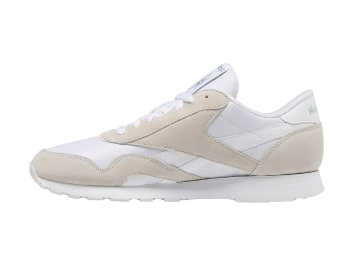 Tenis Reebok blancos de corte bajo con detalles en gamuza clara y suela blanca.