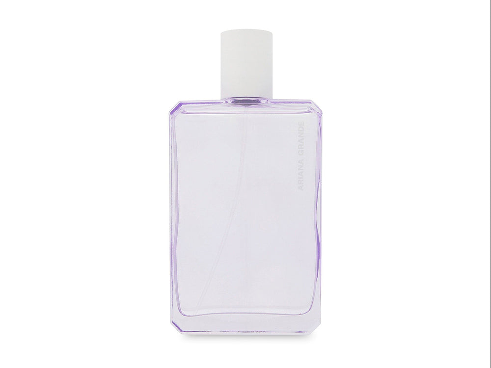 Perfume Ariana Grande God is a Woman con frasco blanco geométrico y caja decorada con flores moradas y blancas.