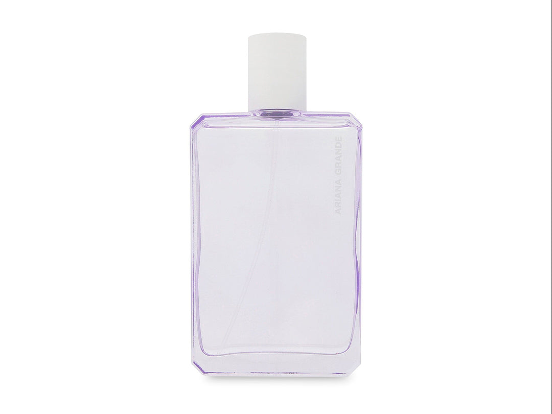 Perfume Ariana Grande God is a Woman con frasco blanco geométrico y caja decorada con flores moradas y blancas.
