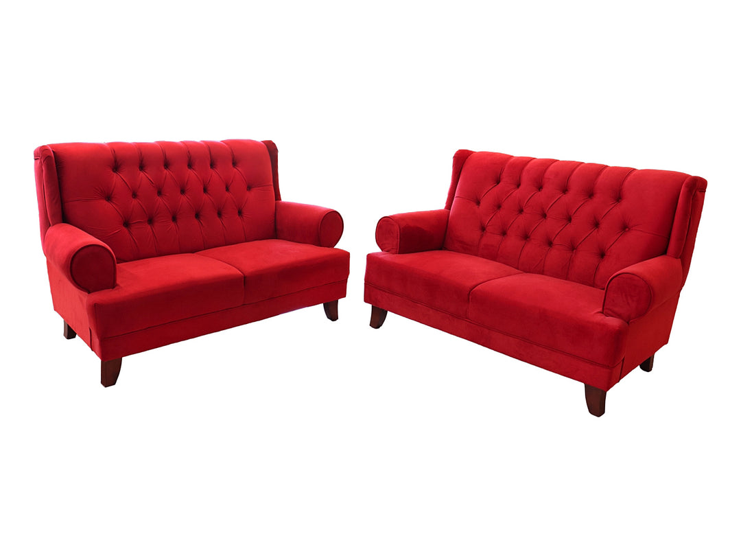 Juego de sala compuesto por dos sofás rojos con respaldo capitoné y patas de madera.