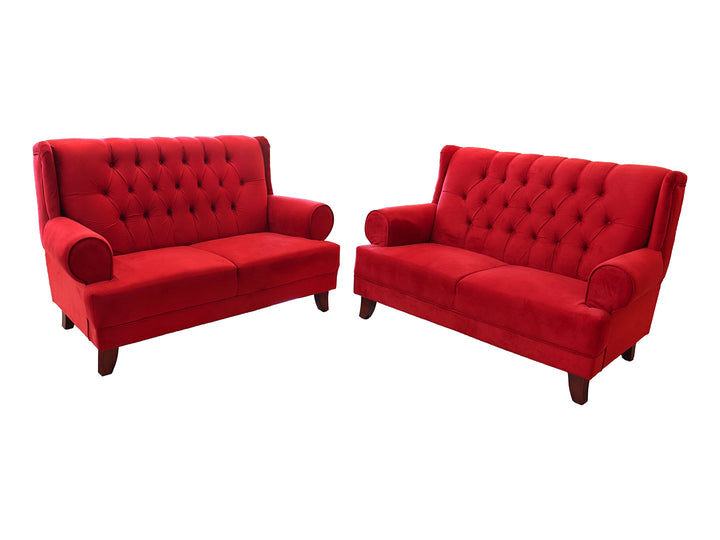 Juego de sala compuesto por dos sofás rojos con respaldo capitoné y patas de madera.