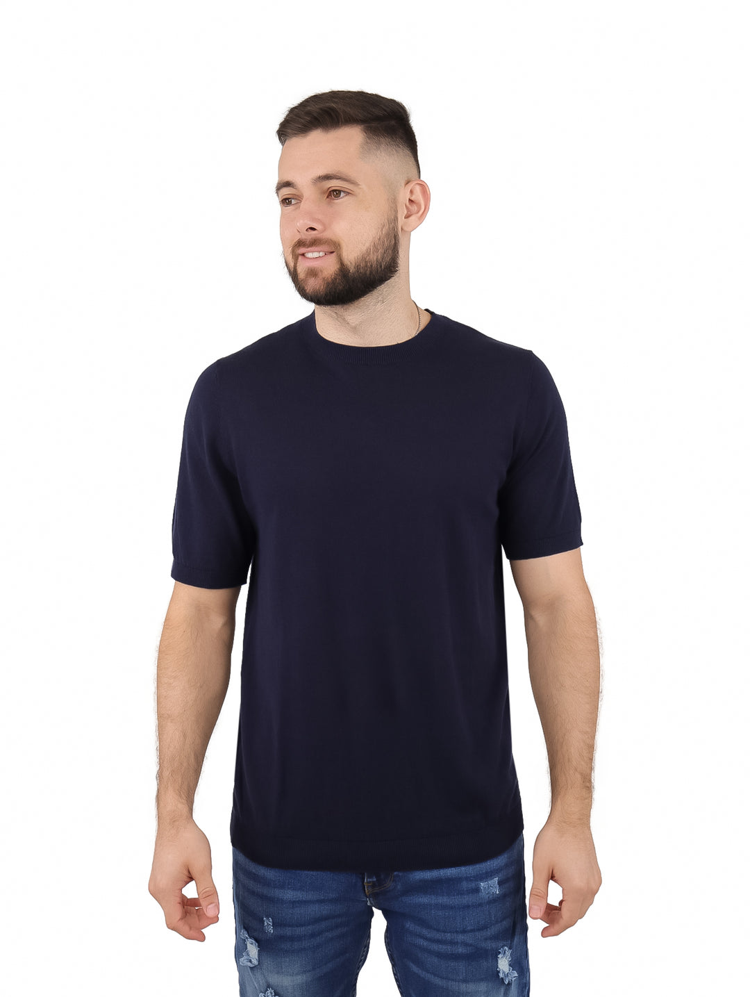Hombre vistiendo una camiseta de manga corta color azul marino con cuello redondo y jeans azules.