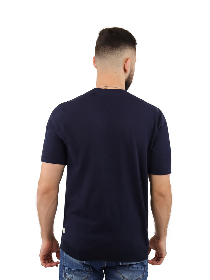 Hombre vistiendo una camiseta de manga corta color azul marino con cuello redondo y jeans azules.