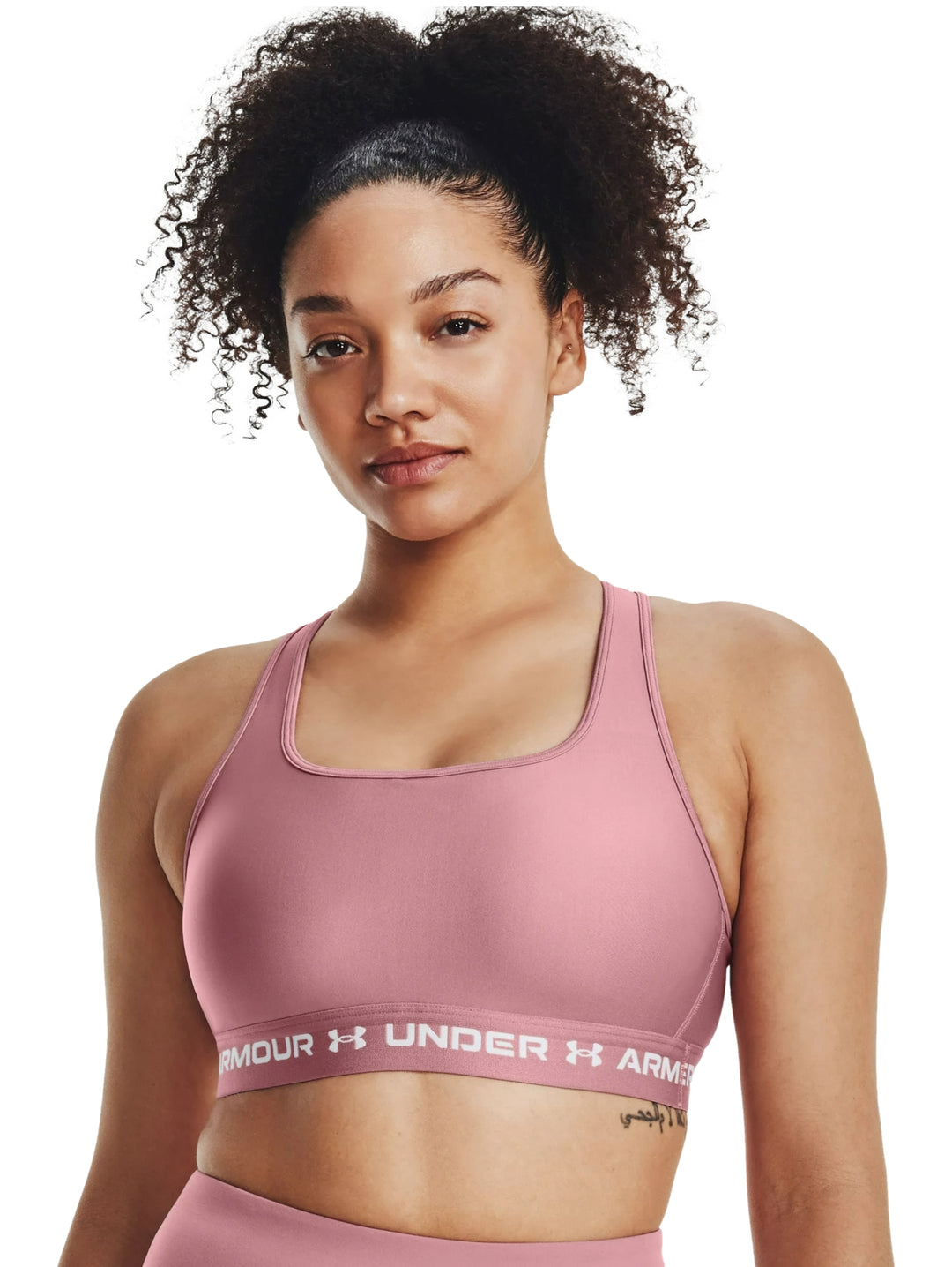 Mujer usando un bra deportivo color rosa de la marca Under Armour.