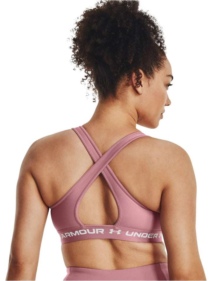 Mujer usando un bra deportivo color rosa de la marca Under Armour.