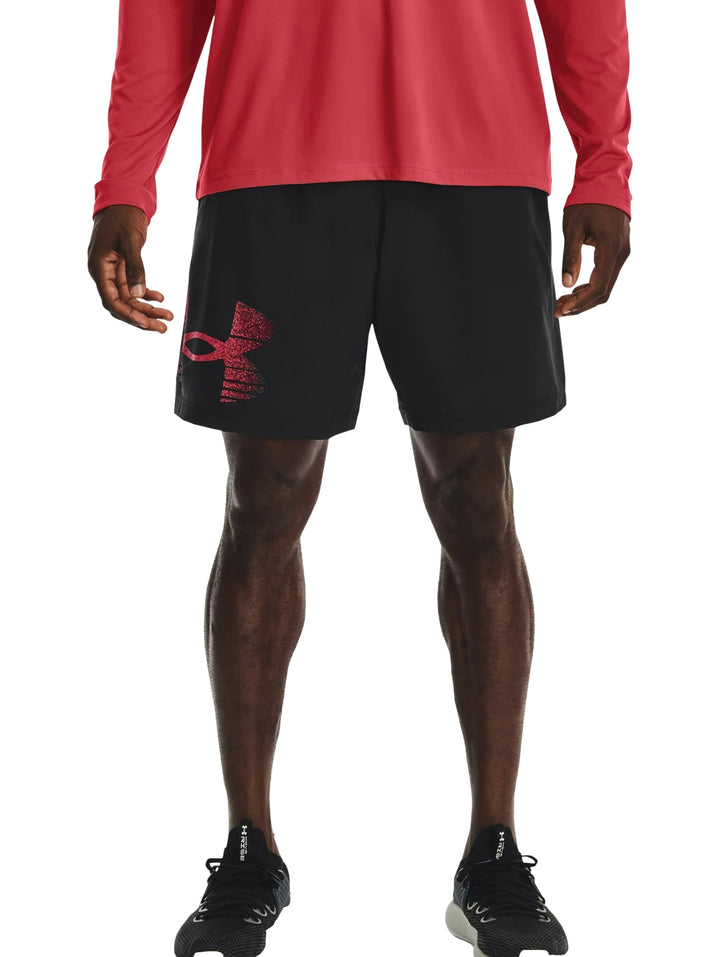 Hombre vistiendo shorts deportivos negros de Under Armour con logotipo gráfico rojo.
