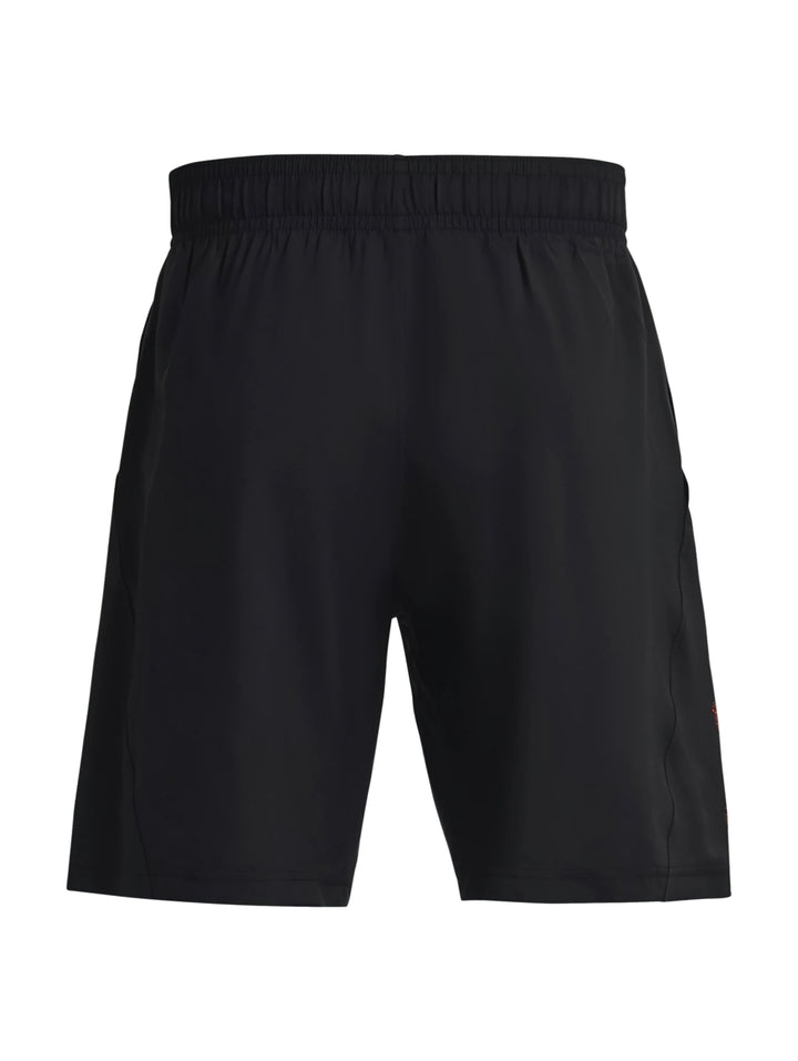 Hombre vistiendo shorts deportivos negros de Under Armour con logotipo gráfico rojo.