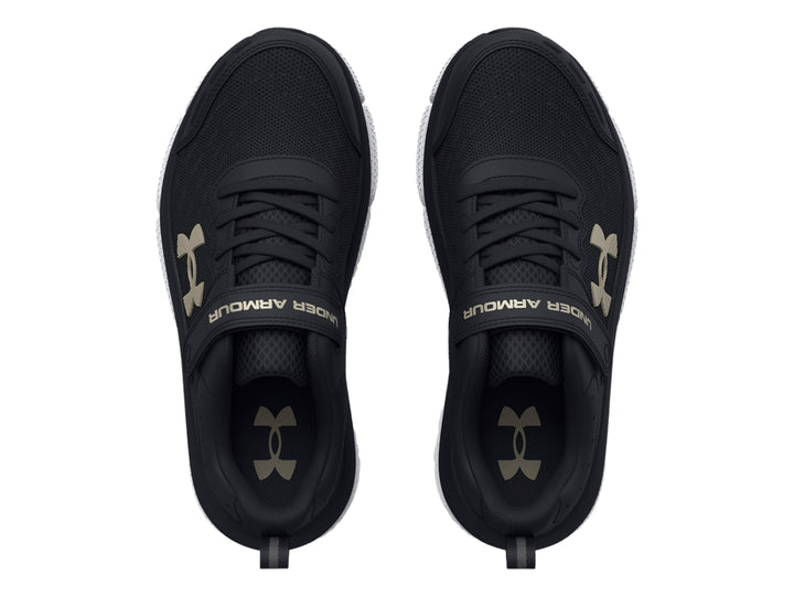 Tenis deportivos Under Armour color negro con suela blanca y cierre de correa de velcro.